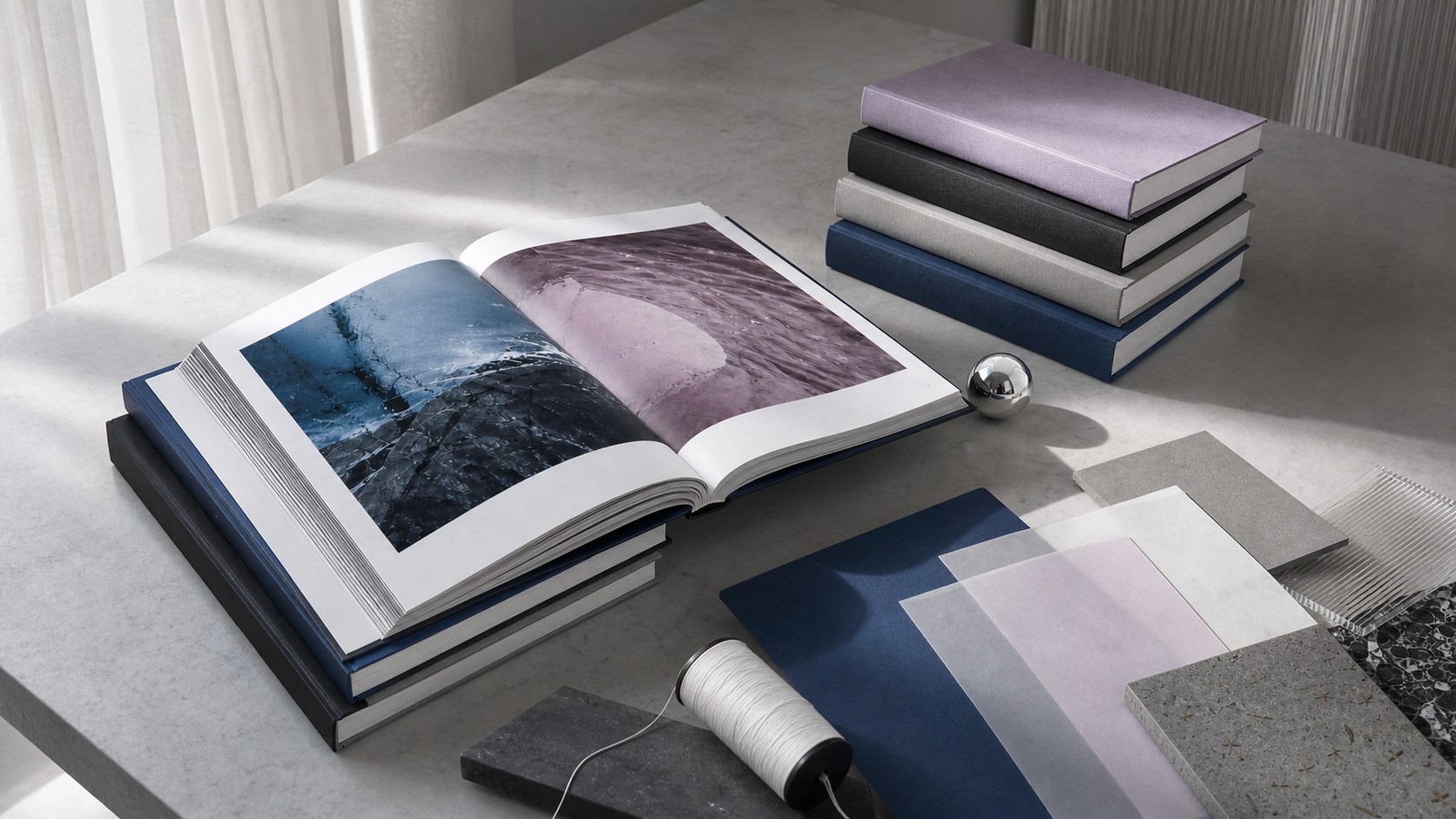 Art books and material studies arranged on a cool studio table
